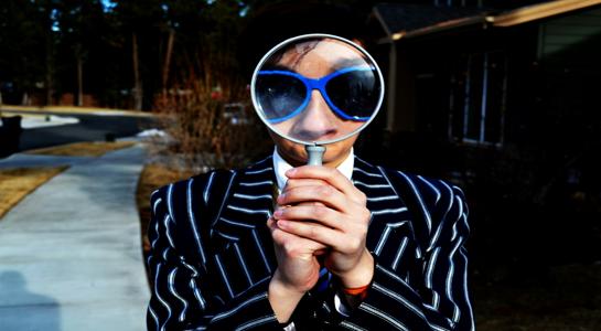 Person holding a magnifying glass up to their face, symbolizing the difficulty AI has in seeing and indexing website content without AEO foundations.